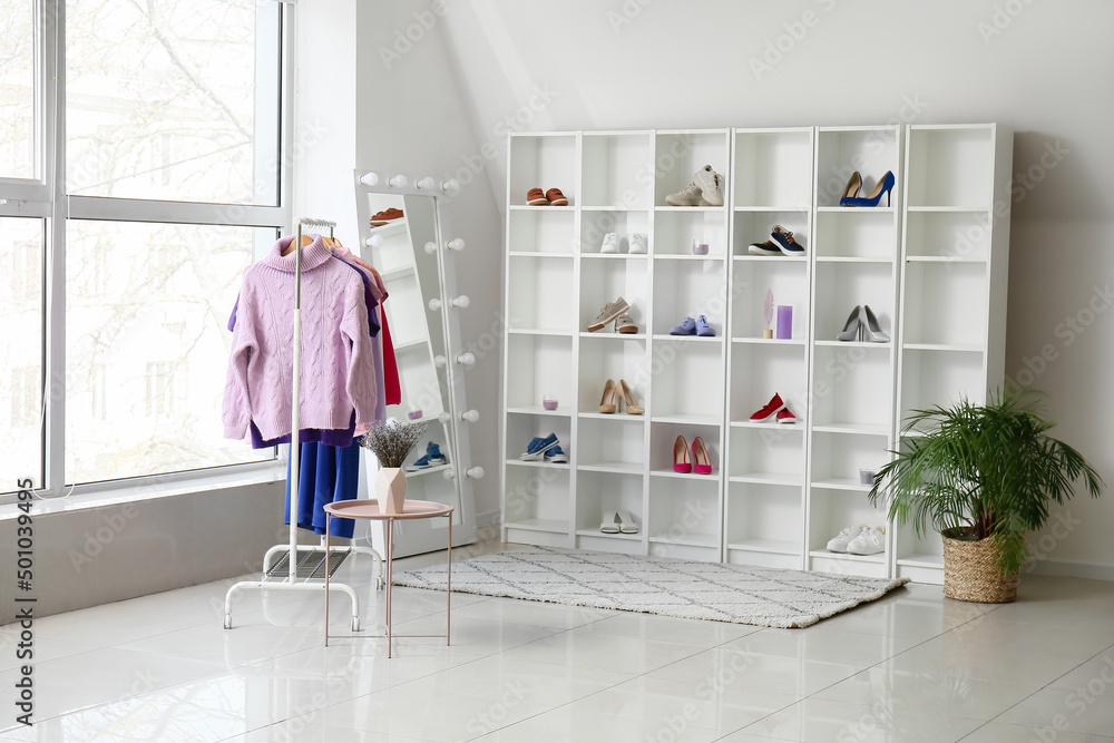 Rack with clothes, shoes, shelving unit and mirror in dressing room