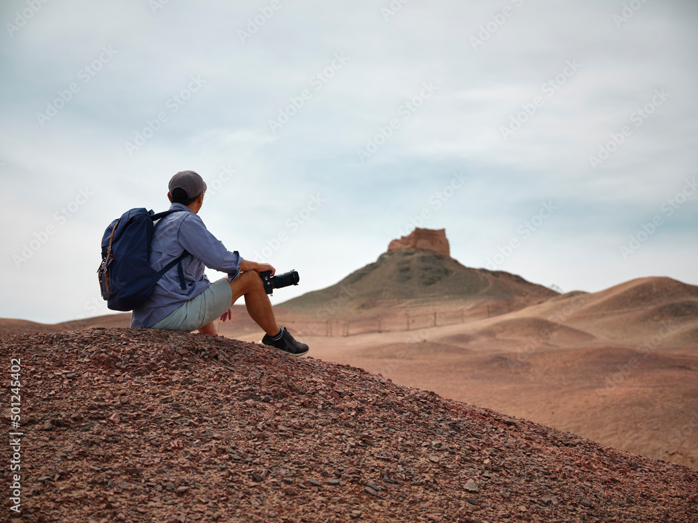亚洲男性背包客摄影师坐在山顶眺望风景