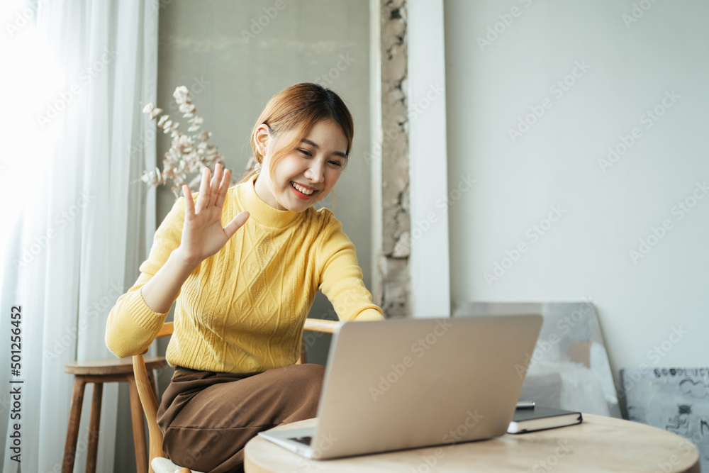 一名亚洲女子在家里用电脑进行视频通话。一个微笑的女孩在网上和老师一起学习。