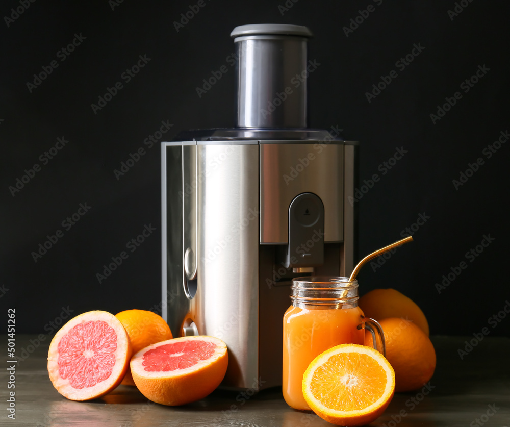 新的现代榨汁机和梅森罐新鲜果汁，木桌上有水果