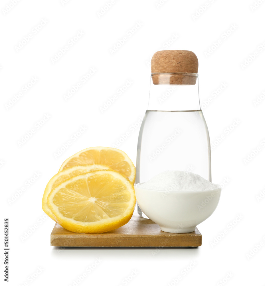 Bowl with baking soda, bottle of water and lemons on white background