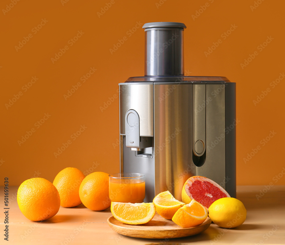 新型现代榨汁机和一杯新鲜果汁，桌上有水果