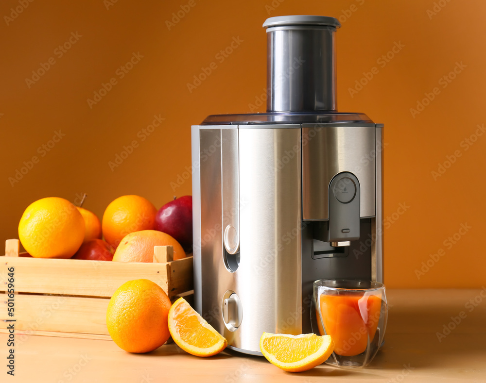 新型现代榨汁机和一杯桌上有水果的新鲜果汁