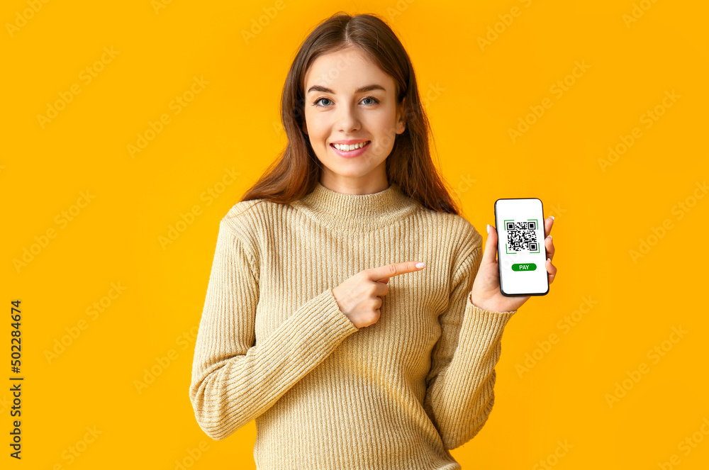 美丽的年轻女子拿着橙色背景下屏幕上有二维码的智能手机