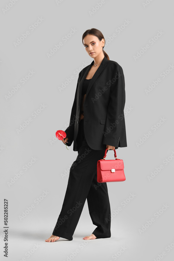 时尚的女人，带着时尚的手提包和灰色背景的花托