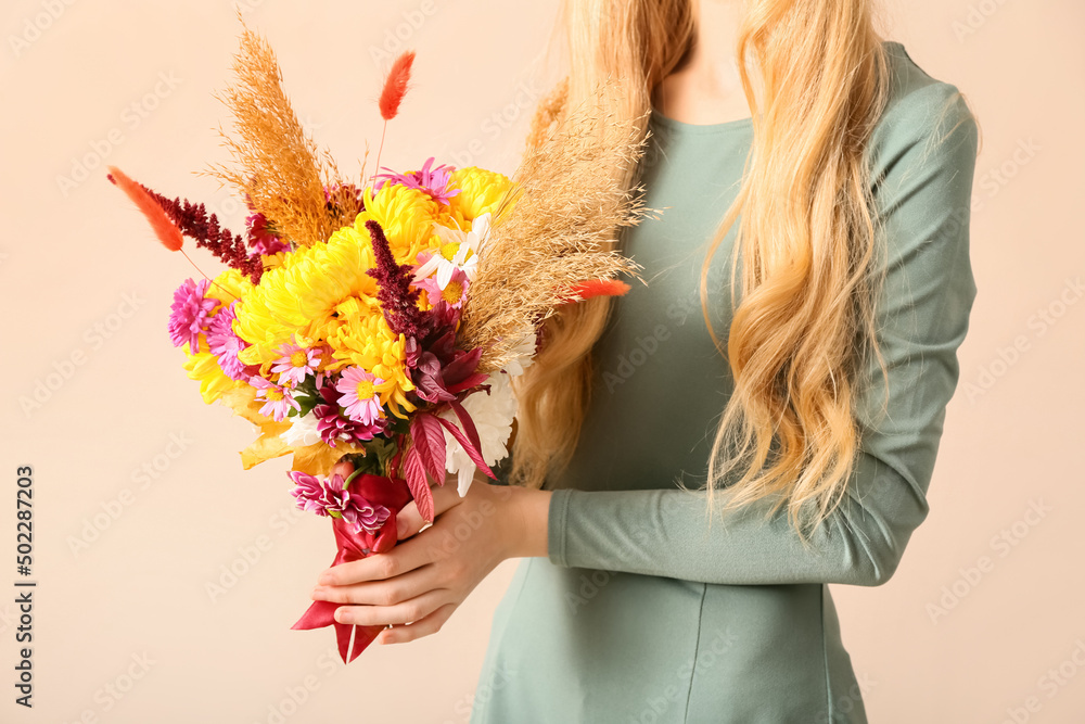 米色背景下带着美丽秋季花束的女人，特写