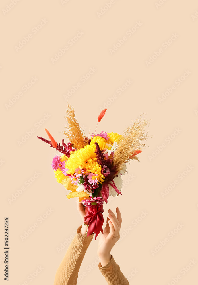 米色背景下带着美丽秋季花束的女人