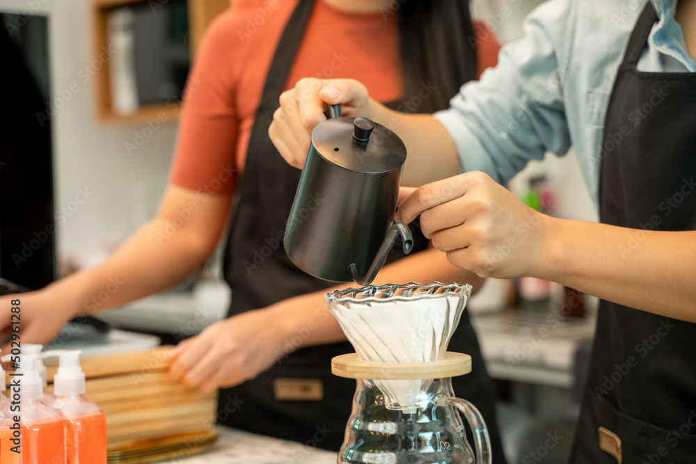 在Entrepr现代咖啡馆的酒吧里，咖啡师把沸水从水壶倒到滴咖啡机上