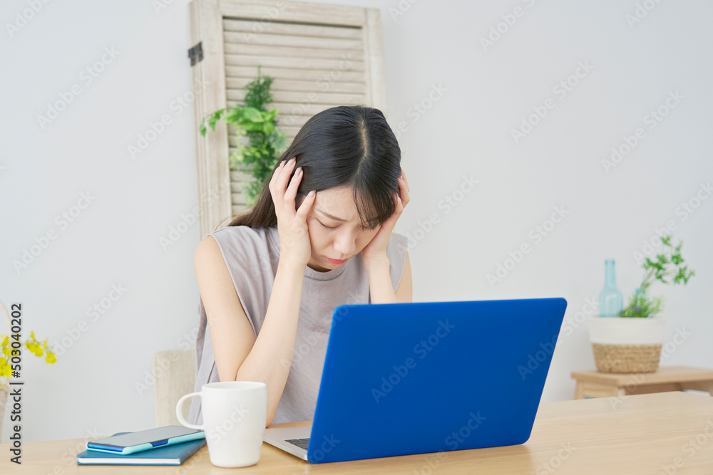 女性　ノートパソコン　頭を抱ええる　リビング
