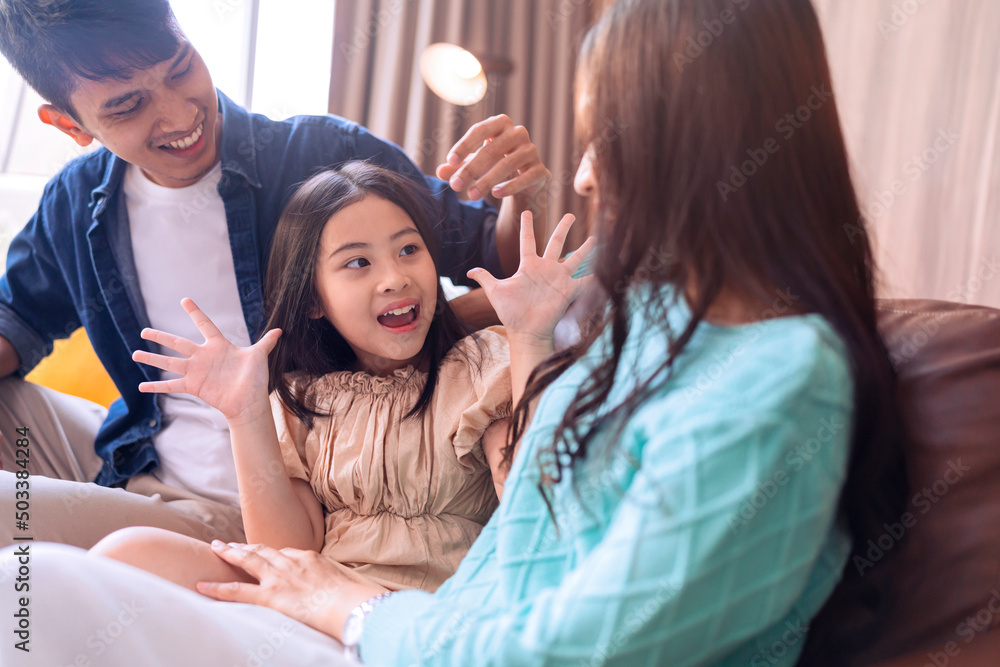 幸福甜蜜的亚洲家庭父亲母亲和女儿一起坐在沙发上看电影