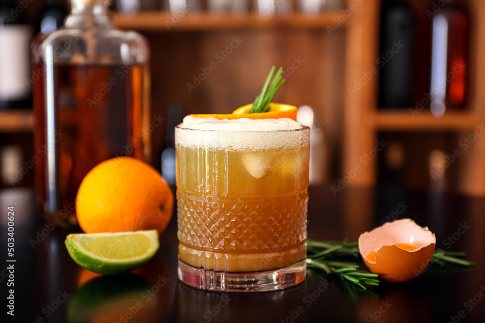 一杯用迷迭香枝、橘子皮和配料装饰的美味威士忌酸鸡尾酒