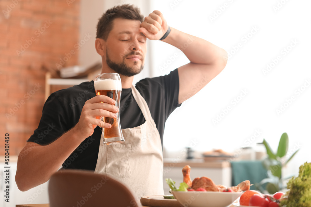 疲惫的男人在厨房做饭后喝啤酒