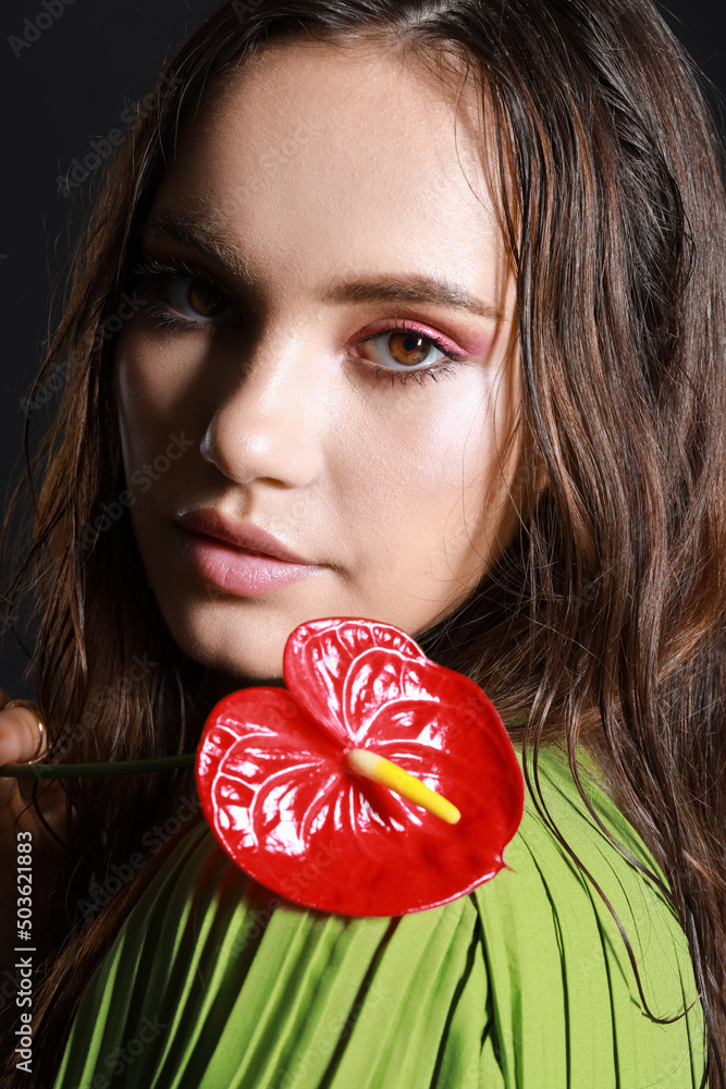 Portrait of young woman with wet hair holding anthurium flower, closeup