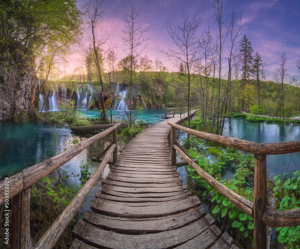 春天日落时，克罗地亚普利特维采湖绿林中的瀑布和木道。多彩的l