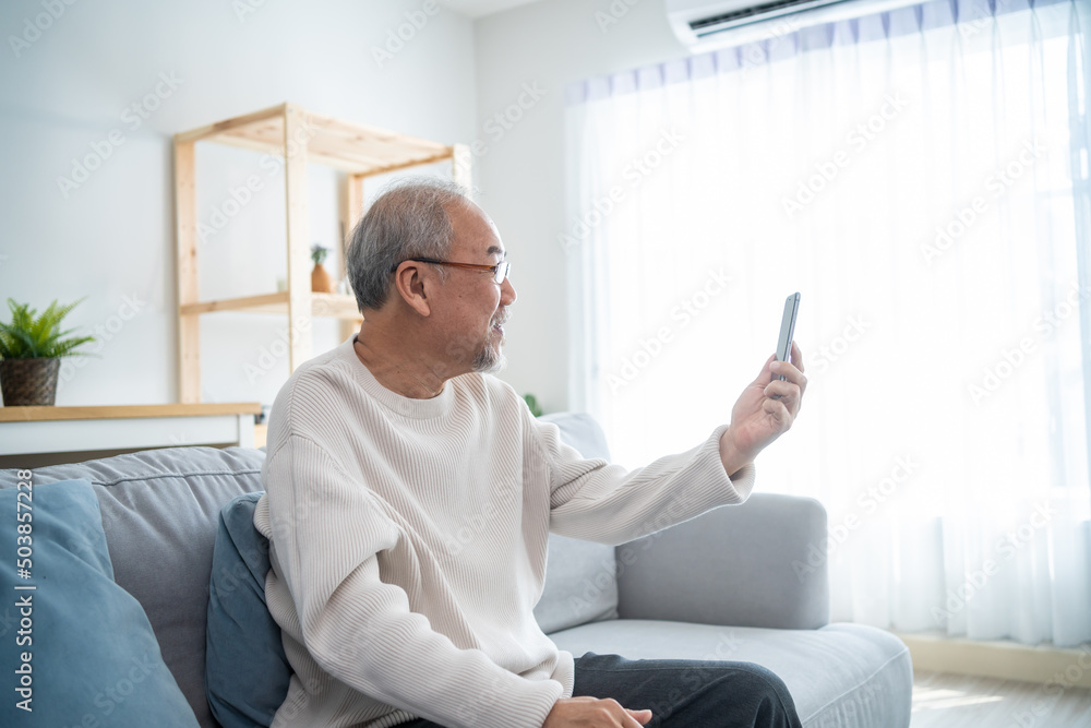 亚洲老年男子在客厅使用手机进行视频通话。