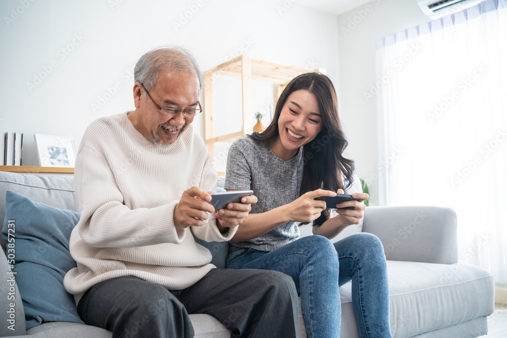 亚洲资深父女在家里一起玩电话游戏。