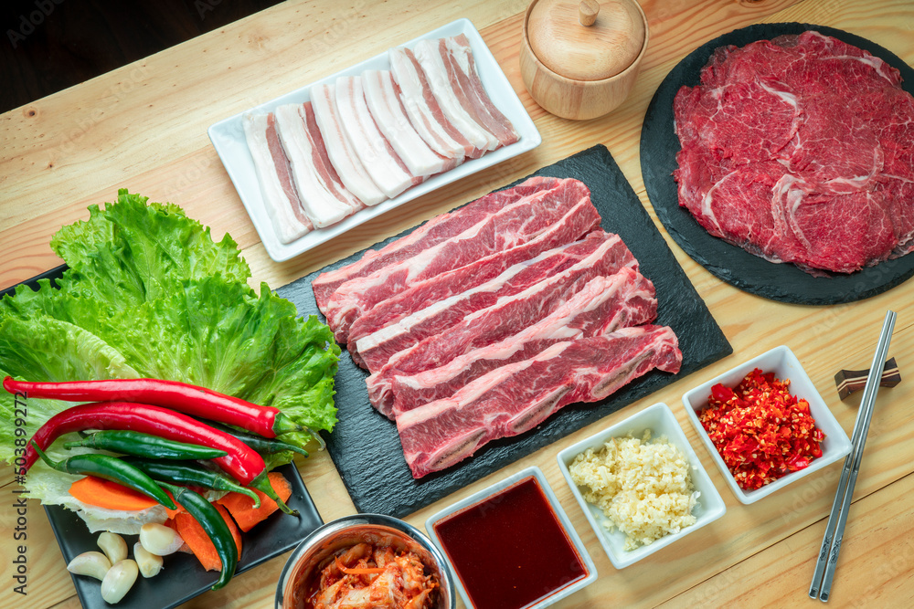 罕见的Wagyu牛肉片，横切短肋牛肉，黑色盘子上的滑猪肚，木头上的红牛肉