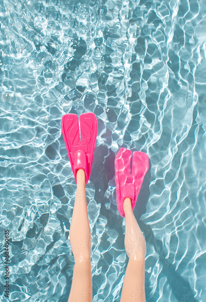 女人的腿上有粉红色的鳍，可以在水中浮潜。简约的夏季海滩度假概念。