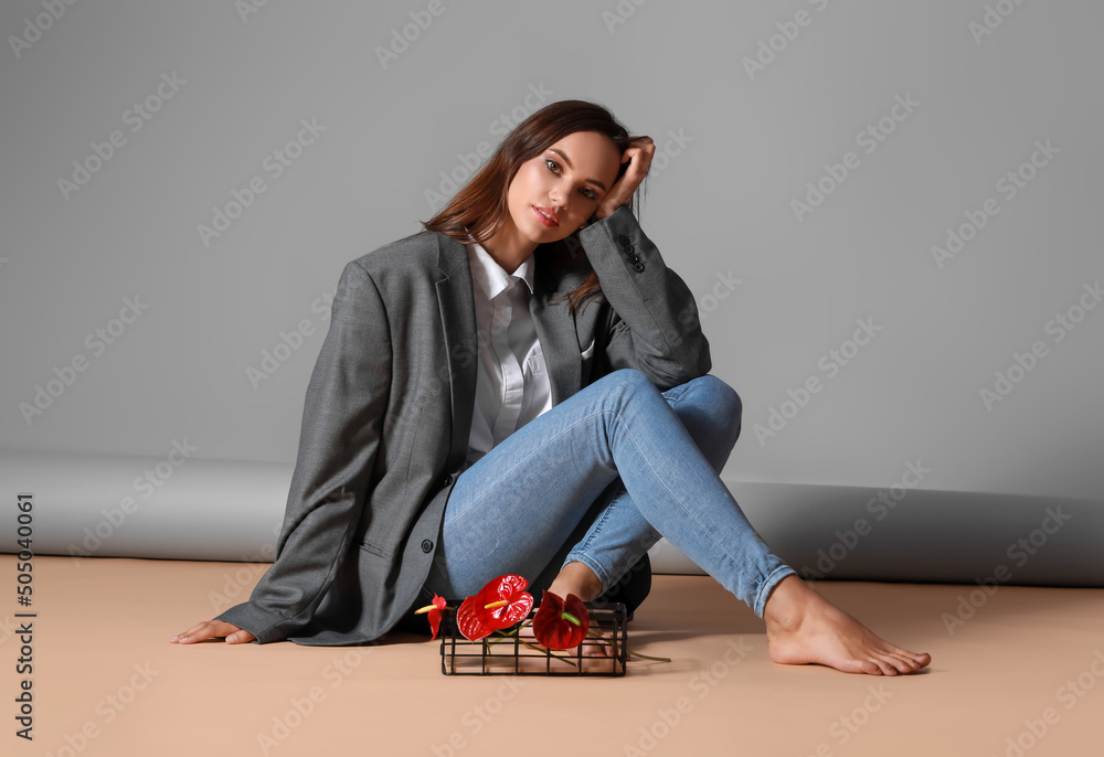 年轻时尚的女人坐在篮子附近的地板上，篮子里有漂亮的花托
