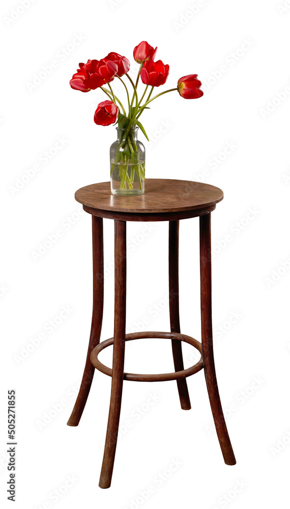 木桌上放着花瓶，上面有花。深色圆桌，红色郁金香孤立在白色上。