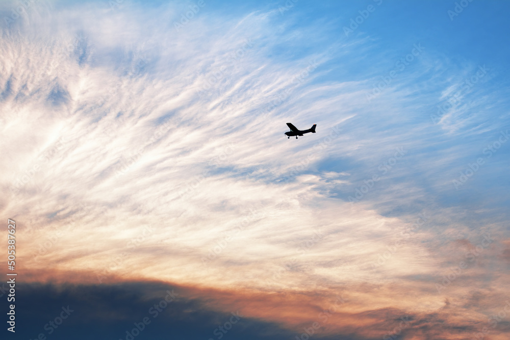 戏剧性日落时天空中的小飞机剪影。浪漫的空中夜晚
