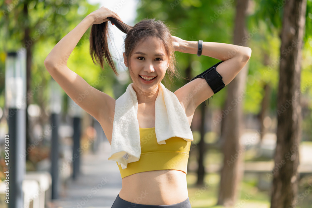 微笑的亚洲女性积极运动生活方式热身跑步前伸展运动，同时安排
