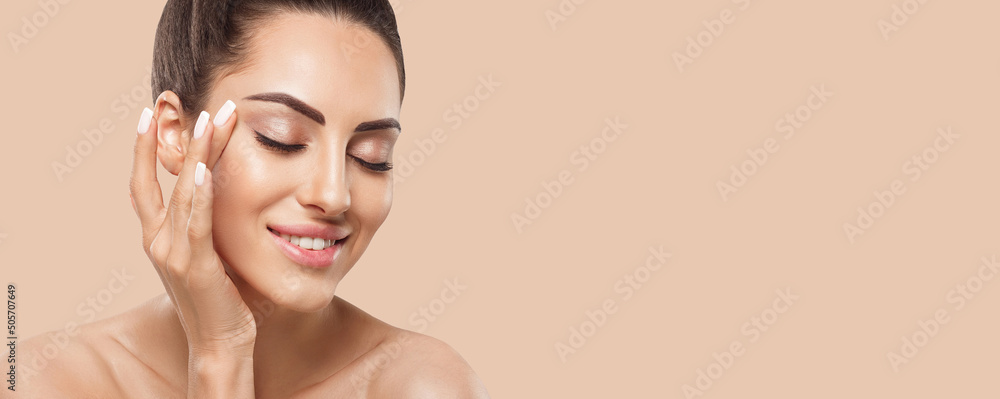 美丽的微笑女性，拥有健康光滑的面部清洁皮肤，涂抹化妆品霜并触摸自己