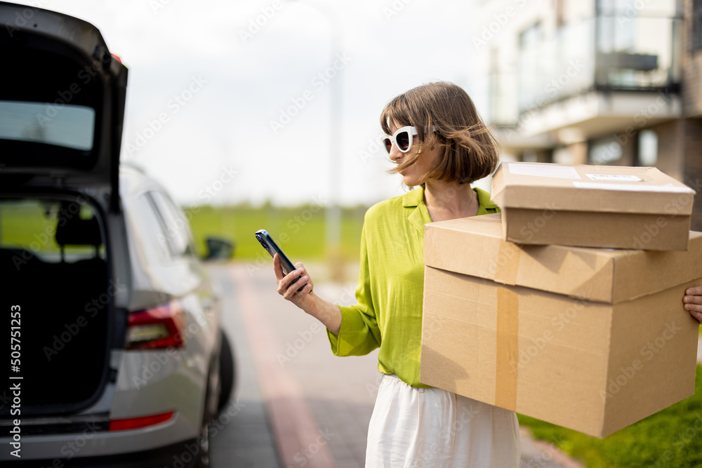 年轻时尚的女人拿着包裹站在户外的街道上，拿着货物，一边打电话