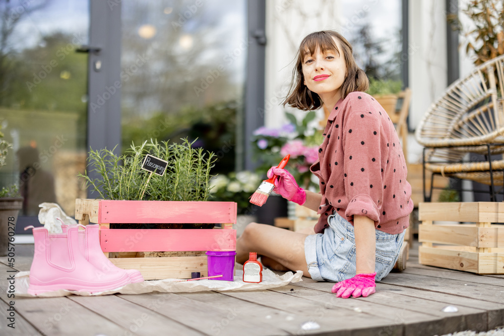 年轻女子将木箱漆成粉红色，在户外露台上做一些翻新家务