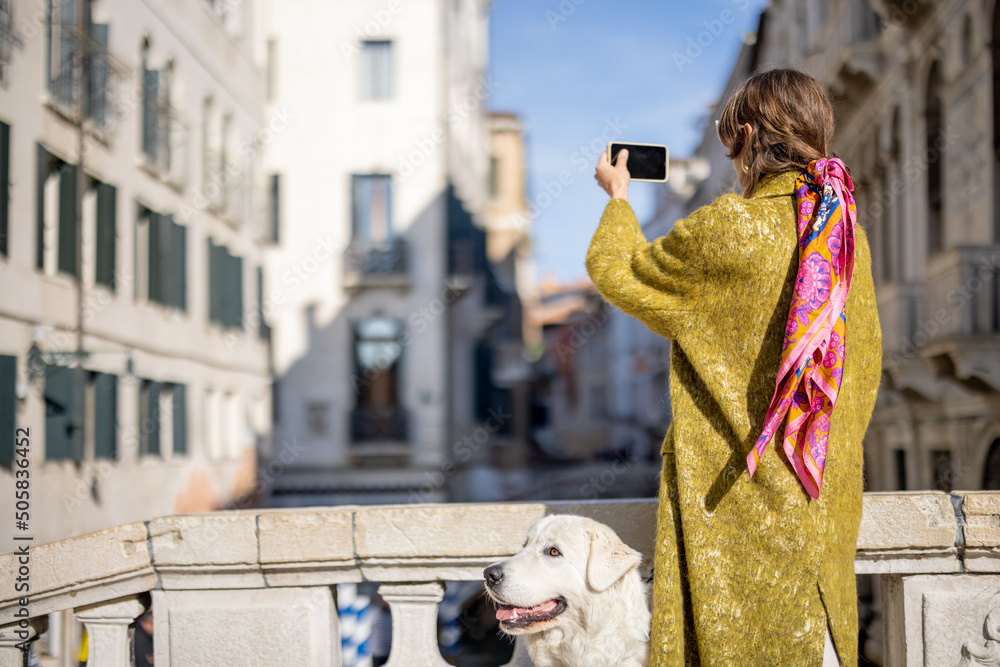 一名女子在威尼斯旅行时在威尼斯运河上拍摄美景。女子穿着