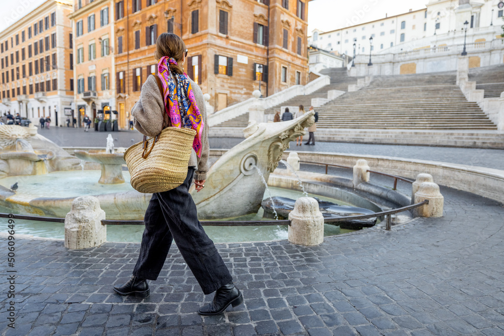 一个女人走在罗马著名的西班牙台阶附近的街道上。一个穿着意大利衣服的优雅女人
