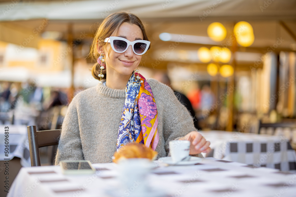 Woman having breakfast with croissant and coffee at traditional italian cafe outdoor. Woman wearing 