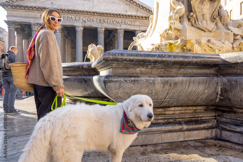一名女子带着她的狗在罗马万神殿附近散步。穿着可爱的白色意大利裙的时尚高加索女子