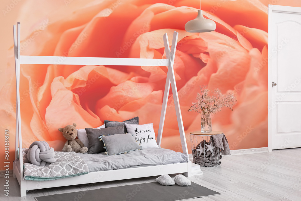 Interior of modern childrens room with comfortable bed and printed beautiful rose flower on wall
