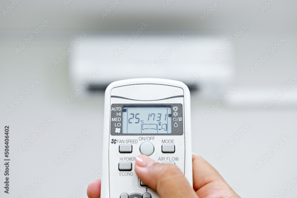 Closeup hand adjust temperature of air conditioner at 25 degree C via remote control. Save energy co
