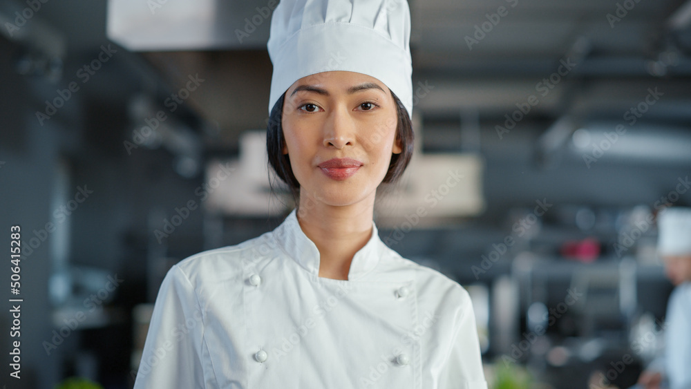 餐厅：亚洲女厨师在现代专业厨房里摆姿势的肖像