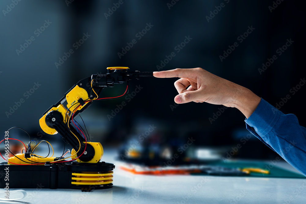 在科学教室里，机器人手臂接触人手。机器人编程概念。
