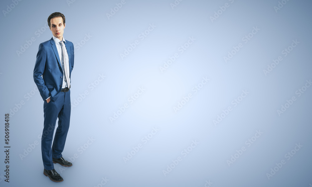 Young confident handsome man in blue suit isolated on blank light blue backgound with empty place fo