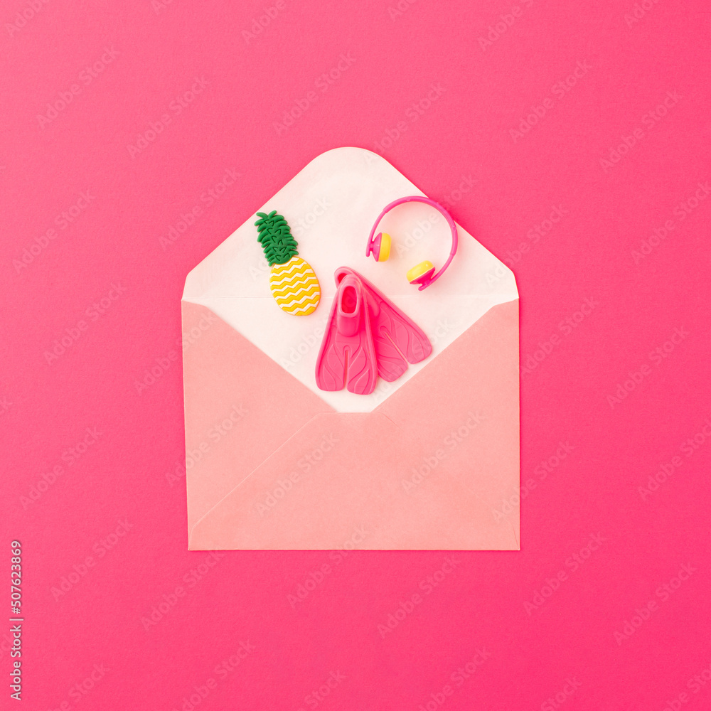Paper envelope with fins, pineapple and headphones on pink background. Summer pleasure concept.