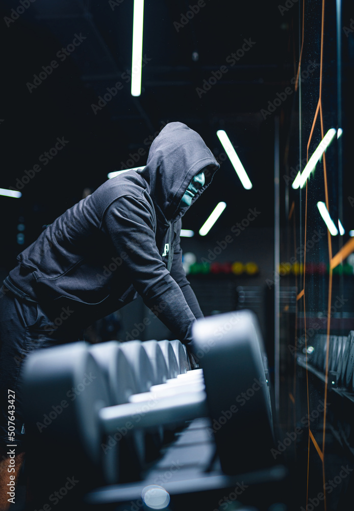 Mystery man posing with hoodie on a black background. Strong fit healthy man in dark hoodie.