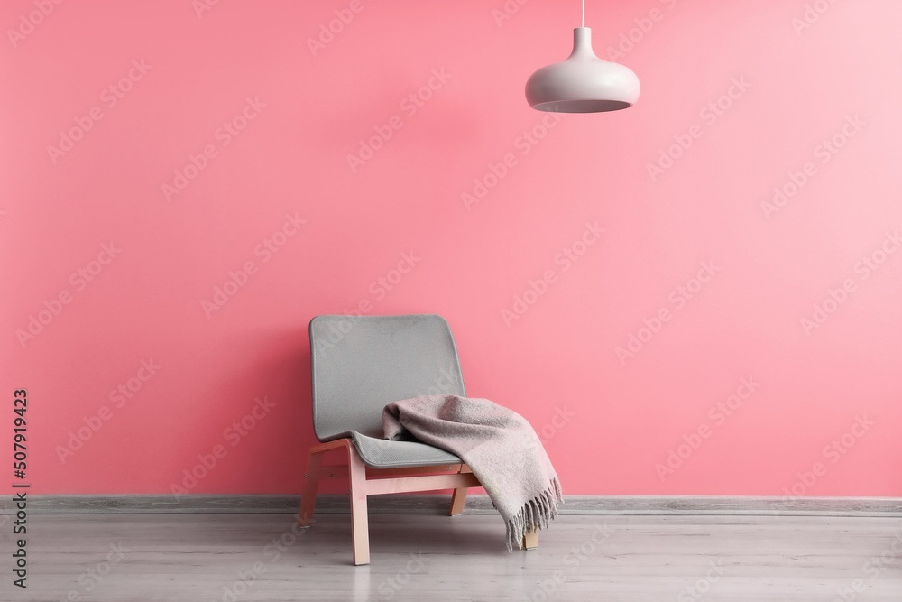 粉色墙壁附近的格子舒适扶手椅