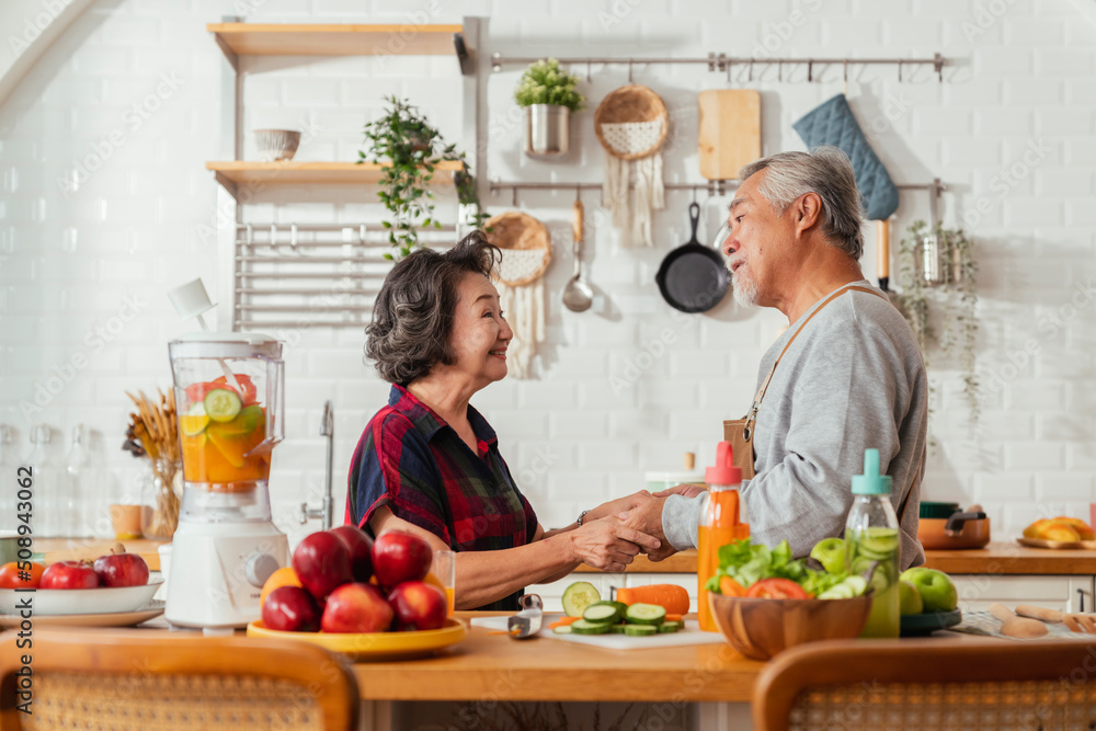 亚洲成年夫妇早上在厨房跳舞，在家一起烹饪健康食品