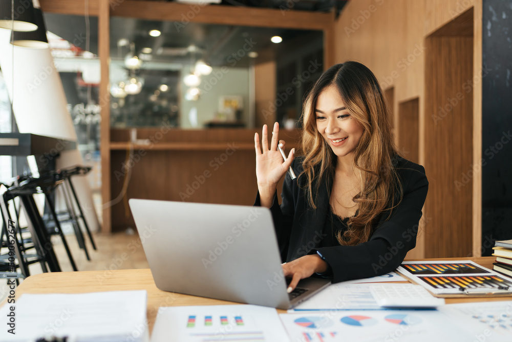 快乐的女商人微笑着在办公室用笔记本电脑打视频电话。
