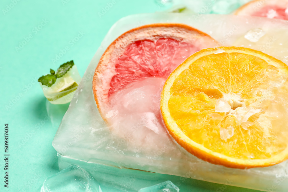 Fresh citrus fruits frozen in ice on turquoise background, closeup