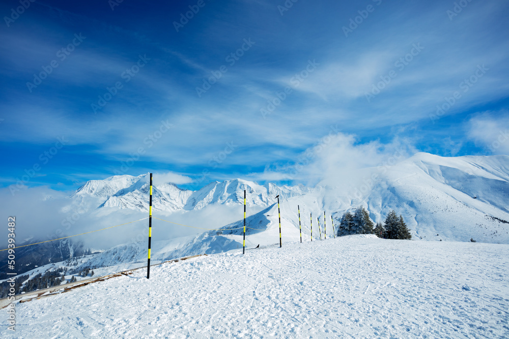 Ski track start on top of a mountain over summits in clouds
