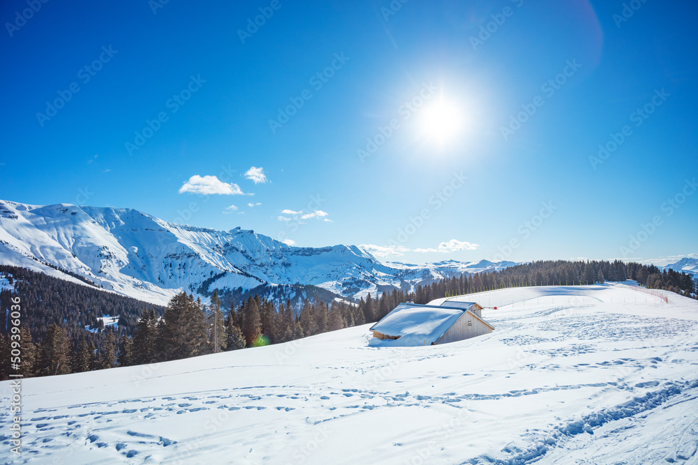 被雪覆盖的小屋和天空中灿烂的阳光的全景