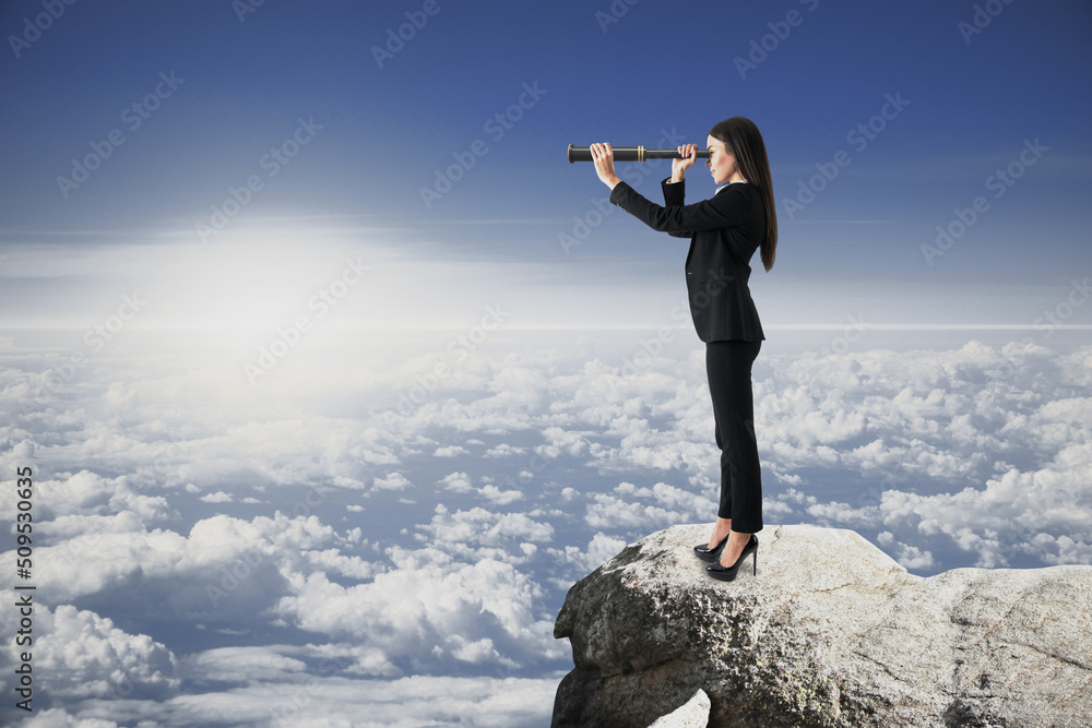 female with telescope standing on cliff and looking into the distance on bright blue sky and clouds 
