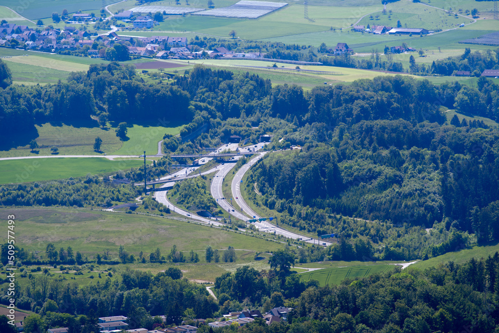 中部地区的鸟瞰图，包括农田、树林、山丘和带隧道入口的高速公路