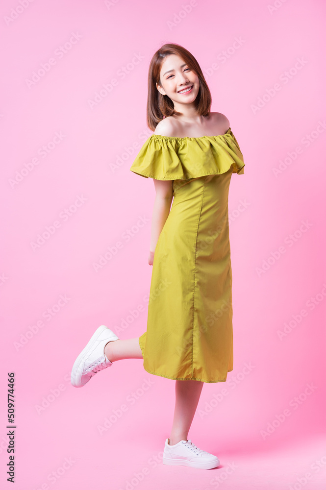 年轻的亚洲女性在粉色背景下穿着绿色连衣裙的照片