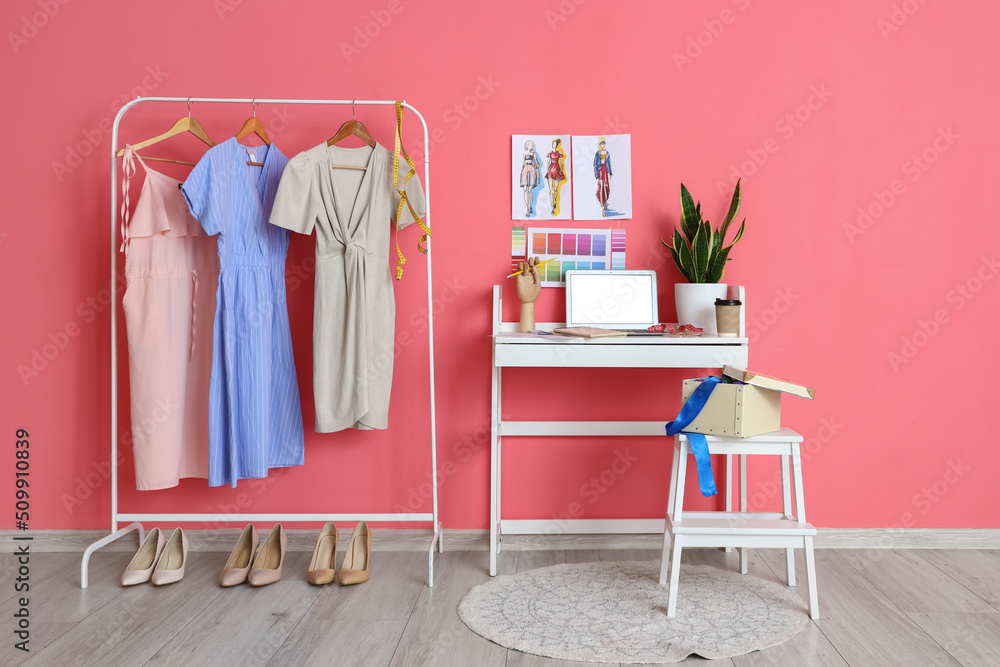 服装设计师的工作场所和粉色墙壁附近的服装货架